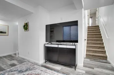 a living room with a tv and a staircase at La Casita with Private Yard 17 Mi to Dtwn Denver in Henderson