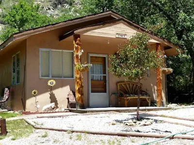 a small house with a tree in front of it at Rural Cabin Rental in Gorgeous Poudre Canyon near Fort Collins, Colorado in Fort Collins