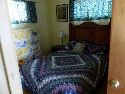 a bedroom with a bed with a blanket on it at Rural Cabin Rental in Gorgeous Poudre Canyon near Fort Collins, Colorado in Fort Collins