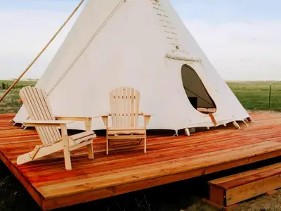 two chairs and a tent on a wooden deck at Cozy and Authentic Tipi Rental on Working Horse Ranch near Denver, Colorado in Hudson