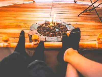 a person with their feet up in front of a fire pit at Cozy and Authentic Tipi Rental on Working Horse Ranch near Denver, Colorado in Hudson