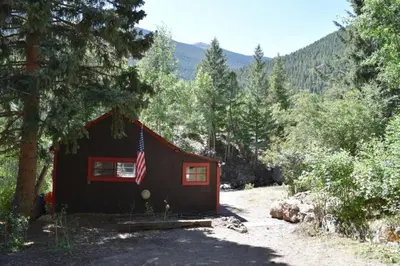a small cabin with an american flag on it at Romantic Hideaway Cottage on Clear Creek in Georgetown, Colorado in Georgetown