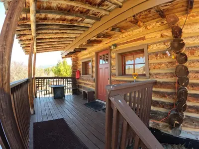 a cabin with a deck with a red door at Arrowhead in Grand Lake