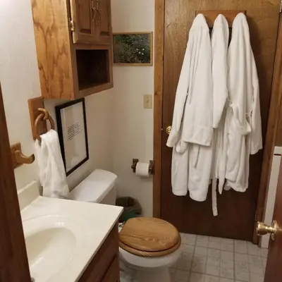 a bathroom with a toilet and towels hanging on a door at Cabin in the Woods in Red Feather Lakes