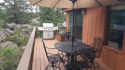 a table and chairs on a deck with an umbrella at Cabin in the Woods in Red Feather Lakes