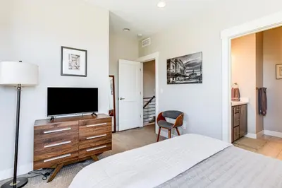a bedroom with a bed and a flat screen tv at Walk to Mile High Stadium Modern Denver Townhome in Denver