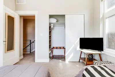 a bedroom with a bed and a flat screen tv at Walk to Mile High Stadium Modern Denver Townhome in Denver