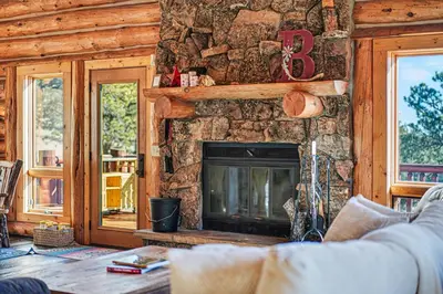 a living room with a fireplace in a log cabin at The Broadmeadow Cabin - VR-25-0005 cabin in Lyons