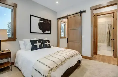 a bedroom with a large bed and a bathroom at 4BR Winter Park Oasis - Sleeps 9 - Ski-In and Hot Tub in Winter Park