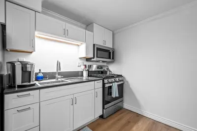 a kitchen with white cabinets and a stove top oven at Quiet Denver Hampden Neighborhood - Tech Center in Denver