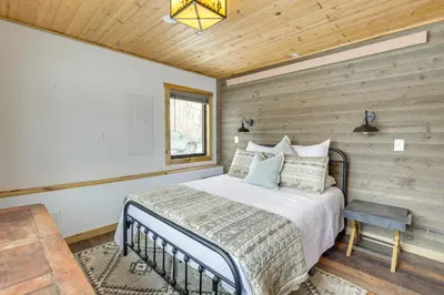 a bedroom with a bed and a wooden wall at Modern Granby Retreat Fish, Hike and Relax! in Granby