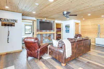 a living room with leather furniture and a flat screen tv at Modern Granby Retreat Fish, Hike and Relax! in Granby