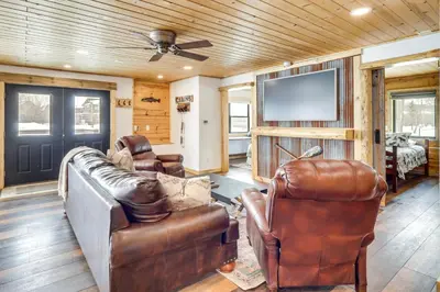 a living room with leather furniture and a flat screen tv at Modern Granby Retreat Fish, Hike and Relax! in Granby