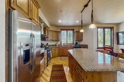 a kitchen with wooden cabinets and a stainless steel refrigerator at Trailside Tranquility in Winter Park