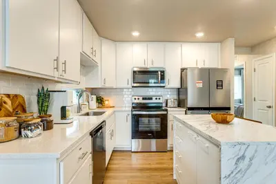 a kitchen with white cabinets and stainless steel appliances at 13 Mi to Dtwn Denver Spacious Home with Balcony! in Denver