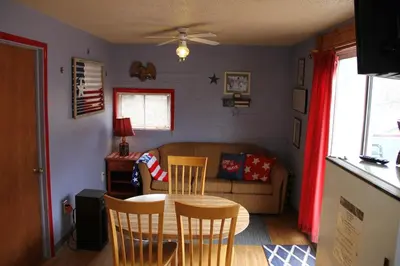 a living room with a table and chairs and a couch at American-Themed Vacation Cabin with a Spacious Deck in Poudre Canyon near Fort Collins, Colorado in Fort Collins