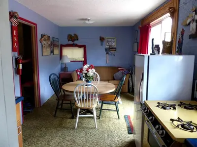 a kitchen with a table and a refrigerator at American-Themed Vacation Cabin with a Spacious Deck in Poudre Canyon near Fort Collins, Colorado in Fort Collins
