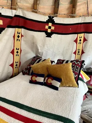 a bed with some pillows on top of it at Raven's Ridge Luxurious Tipi in Golden, Colorado in Golden