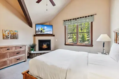 a bedroom with a white bed and a fireplace at Spacious Ski Townhome with Game Room Fun in Breckenridge