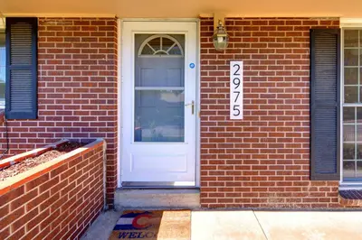 a white door on a brick house with a sign on it at Family Retreat! By Denver + Hot Tub, Sleeps 10! in Wheat Ridge
