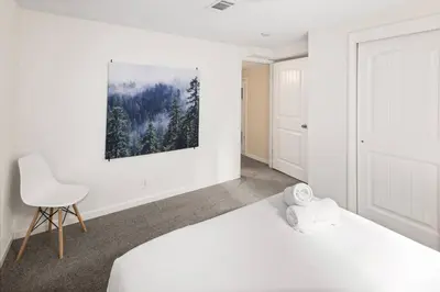 a bedroom with a white bed and a chair at Family Retreat! By Denver + Hot Tub, Sleeps 10! in Wheat Ridge