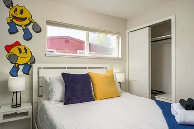 a bedroom with a white bed and a window at Mini Golf • Fire Pit • Hot Tub | Game House for 14 in Arvada