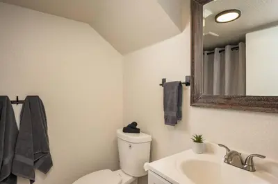 a bathroom with a toilet and a sink and a mirror at Mini Golf • Fire Pit • Hot Tub | Game House for 14 in Arvada