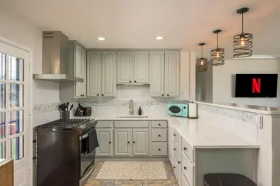 a kitchen with white cabinets and a black refrigerator at Mini Golf • Fire Pit • Hot Tub | Game House for 14 in Arvada