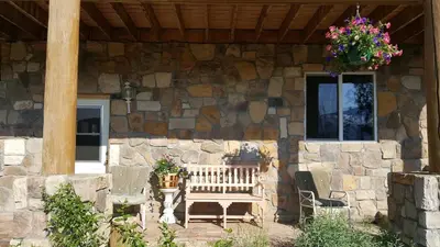 a wooden bench sitting in front of a stone house at Bluejay bunkhouse in Grand Lake