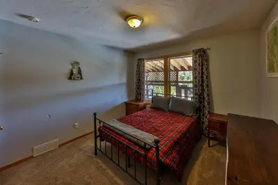 a bedroom with a bed with a red blanket and a window at Bluejay bunkhouse in Grand Lake