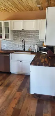 a kitchen with white cabinets and a wooden floor at Cowboy cabin in Grand Lake