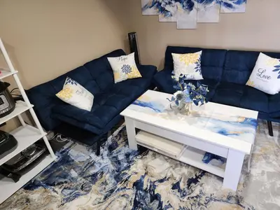 a living room with a blue couch and a white table at Entire Basement with private Entrance within walking distance from the Gaylord hotel in Aurora