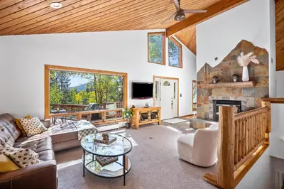 a living room with a couch and a fireplace at Nestled Inn Vacation Home Rental Evergreen - Trails, Views, Hot Tub, Skiing! in Evergreen