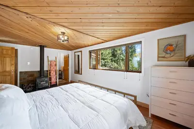 a bedroom with a large white bed and a window at Nestled Inn Vacation Home Rental Evergreen - Trails, Views, Hot Tub, Skiing! in Evergreen