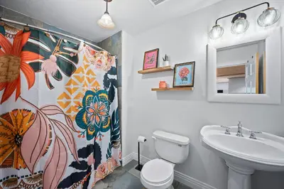 a bathroom with a sink and a toilet and a shower curtain at Nestled Inn Vacation Home Rental Evergreen - Trails, Views, Hot Tub, Skiing! in Evergreen
