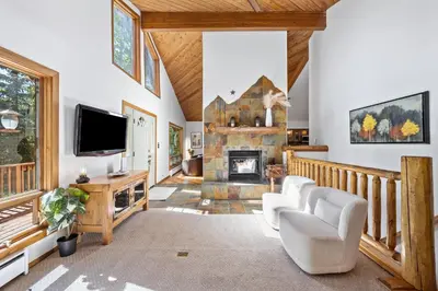 a living room with a fireplace and a tv at Nestled Inn Vacation Home Rental Evergreen - Trails, Views, Hot Tub, Skiing! in Evergreen