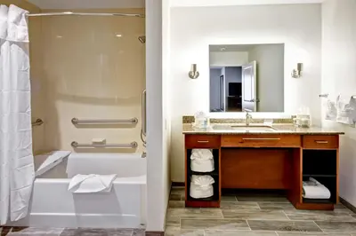 a bathroom with a sink and a tub and a mirror at Homewood Suites by Hilton Greeley in Greeley
