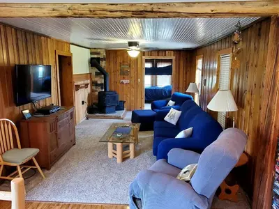 a living room with a blue couch and a tv at Beautiful Cabin with Fire Pit and Deck in Foxpark, Wyoming in Foxpark