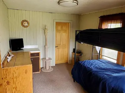 a bedroom with a bed and a desk with a television at Beautiful Cabin with Fire Pit and Deck in Foxpark, Wyoming in Foxpark