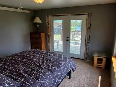 a bedroom with a bed and a sliding glass door at Beautiful Cabin with Fire Pit and Deck in Foxpark, Wyoming in Foxpark