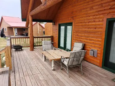 a wooden deck with a table and chairs on a cabin at Beautiful Cabin with Fire Pit and Deck in Foxpark, Wyoming in Foxpark