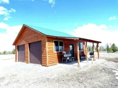 a cabin in the middle of a field at Beautiful Cabin with Fire Pit and Deck in Foxpark, Wyoming in Foxpark