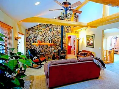 a living room with a couch and a stone wall at Spacious Cabin with Breathtaking Views near Rocky Mountain National Park, Colorado in Estes Park