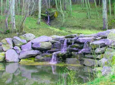 a stone wall next to a pond with a waterfall at Spacious Cabin with Breathtaking Views near Rocky Mountain National Park, Colorado in Estes Park