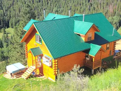 a house with a green roof on a hill at Spacious Cabin Rental with a Hot Tub for a Weekend Getaway near Denver, Colorado in Idaho Springs