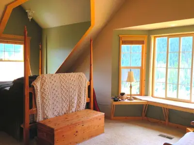 a room with a bed and a chair and windows at Spacious Cabin Rental with a Hot Tub for a Weekend Getaway near Denver, Colorado in Idaho Springs