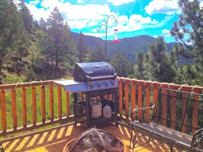 a grill sitting on top of a deck with a bench at Spacious Cabin Rental with a Hot Tub for a Weekend Getaway near Denver, Colorado in Idaho Springs