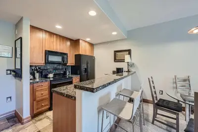 a kitchen with wooden cabinets and a counter with chairs at Cozy 1BR Near Trails with Shuttle to Slopes and Town in Breckenridge