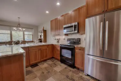 a kitchen with wooden cabinets and a stainless steel refrigerator at Beautiful Unit in Quiet Area with Shuttle to Slopes in Breckenridge