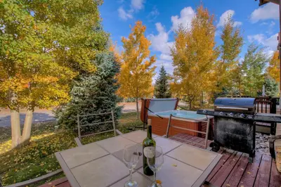 a table with wine glasses and a grill on a deck at Beautiful Unit in Quiet Area with Shuttle to Slopes in Breckenridge